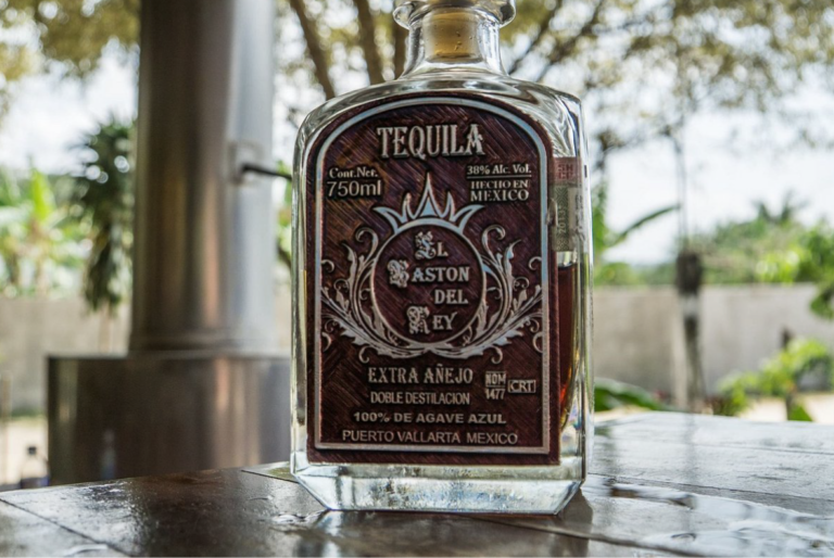 Botella de tequila sobre mesa de madera con plantas