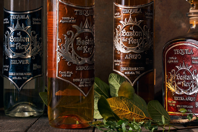 Cuatro botellas de tequila con plantas sobre mesa de madera