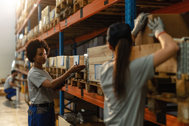 Trabajadora afroamericana comunicándose con su compañera mientras prepara un envío en un almacén industrial. Almacenamiento Guadalajara
