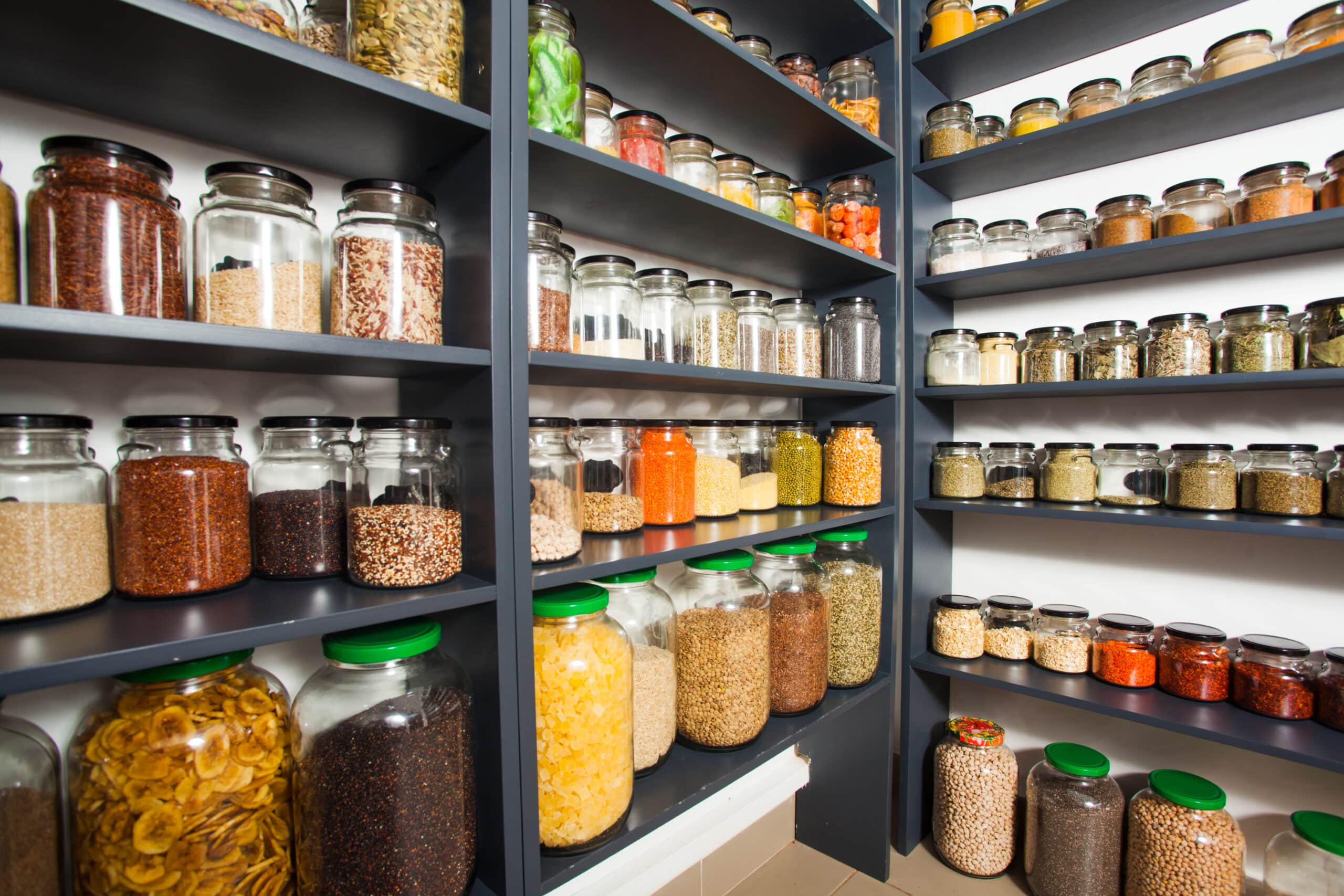 Shelf in a shop with colorful natural spices and powders in glass jars on display. Dry fruits and nuts, cereals in the shop. Grosery market and healthy food and zero waste concept