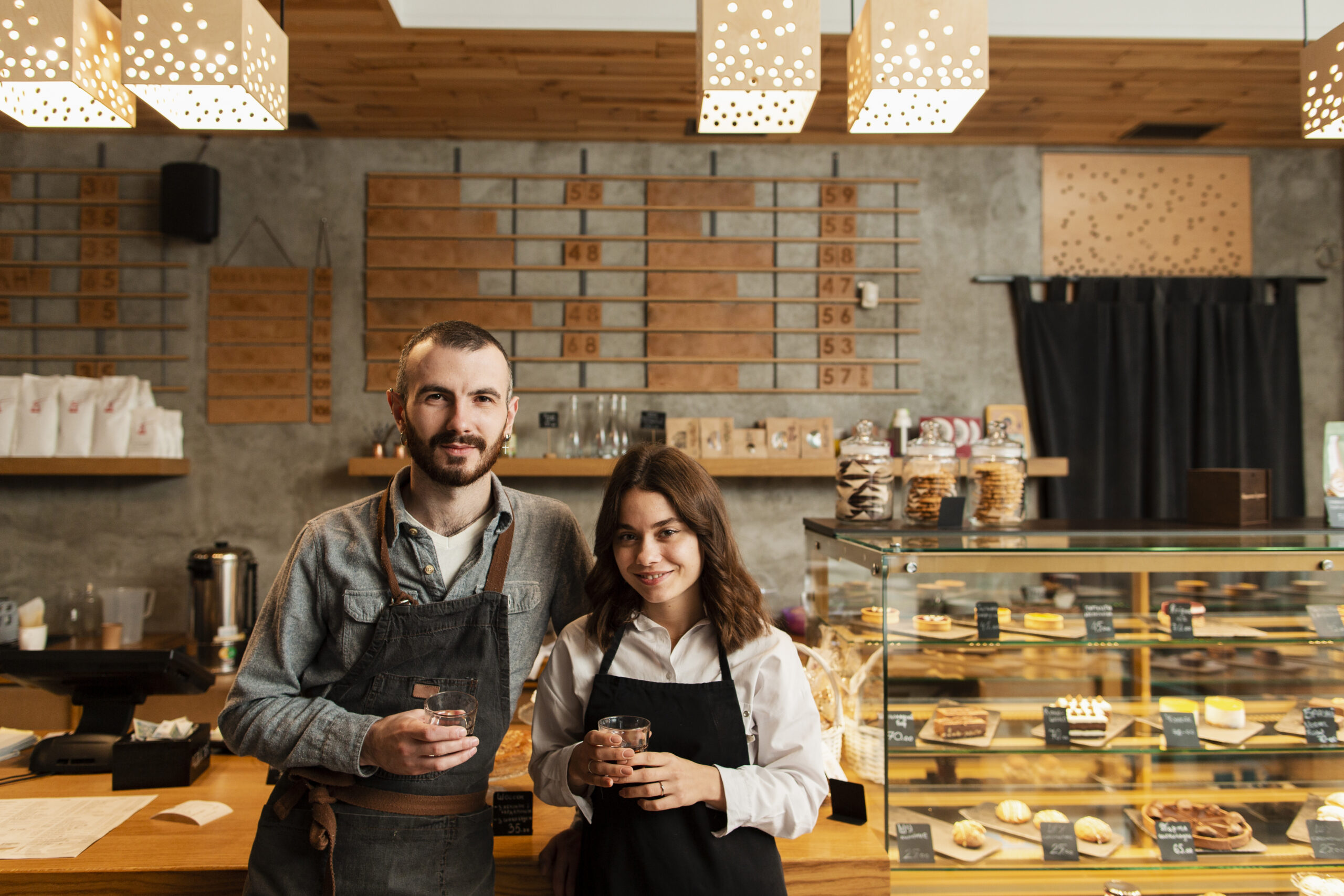 couple-aprons-posing-with-cups-coffee