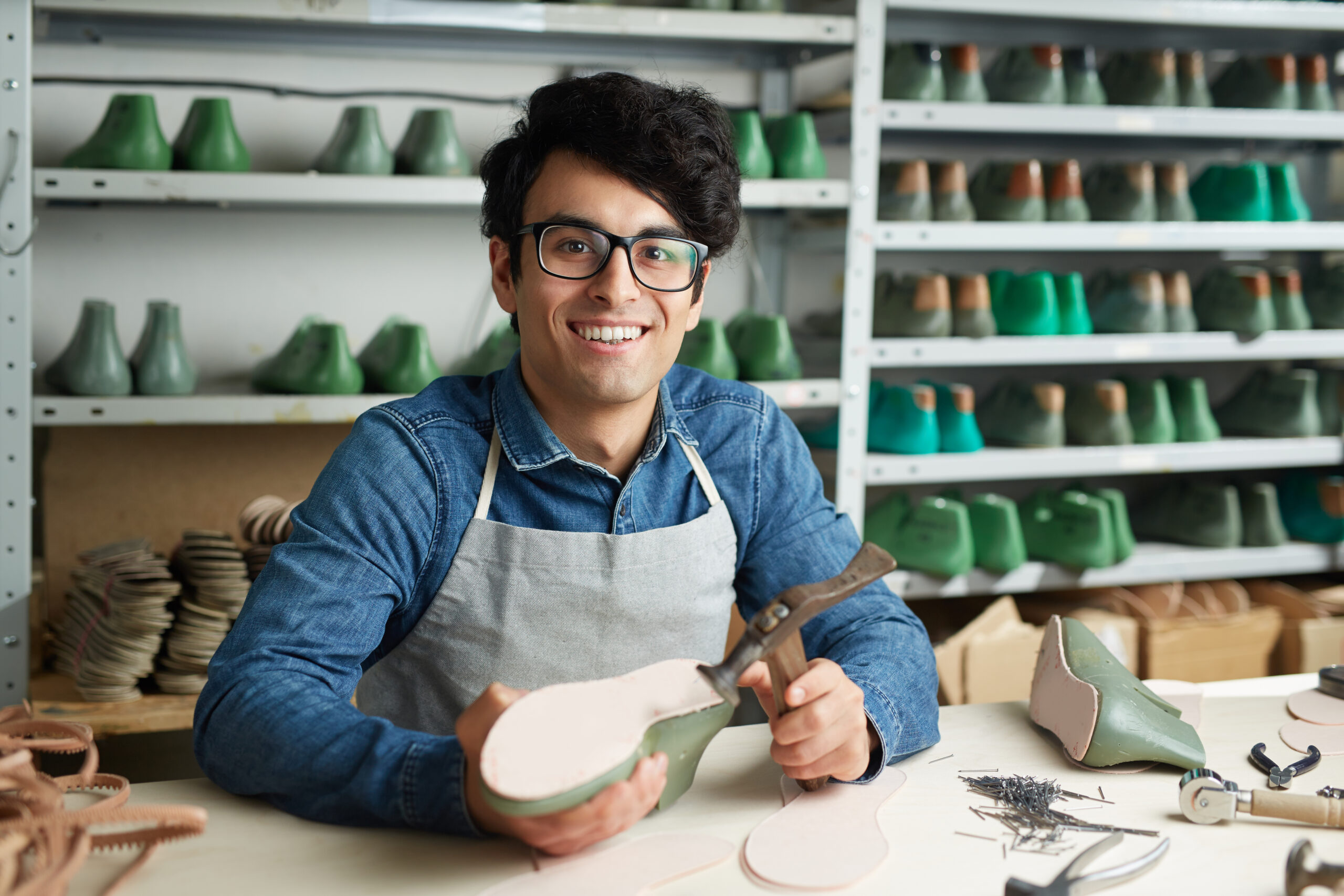Self-employed shoemaker or repairman looking at camera during work